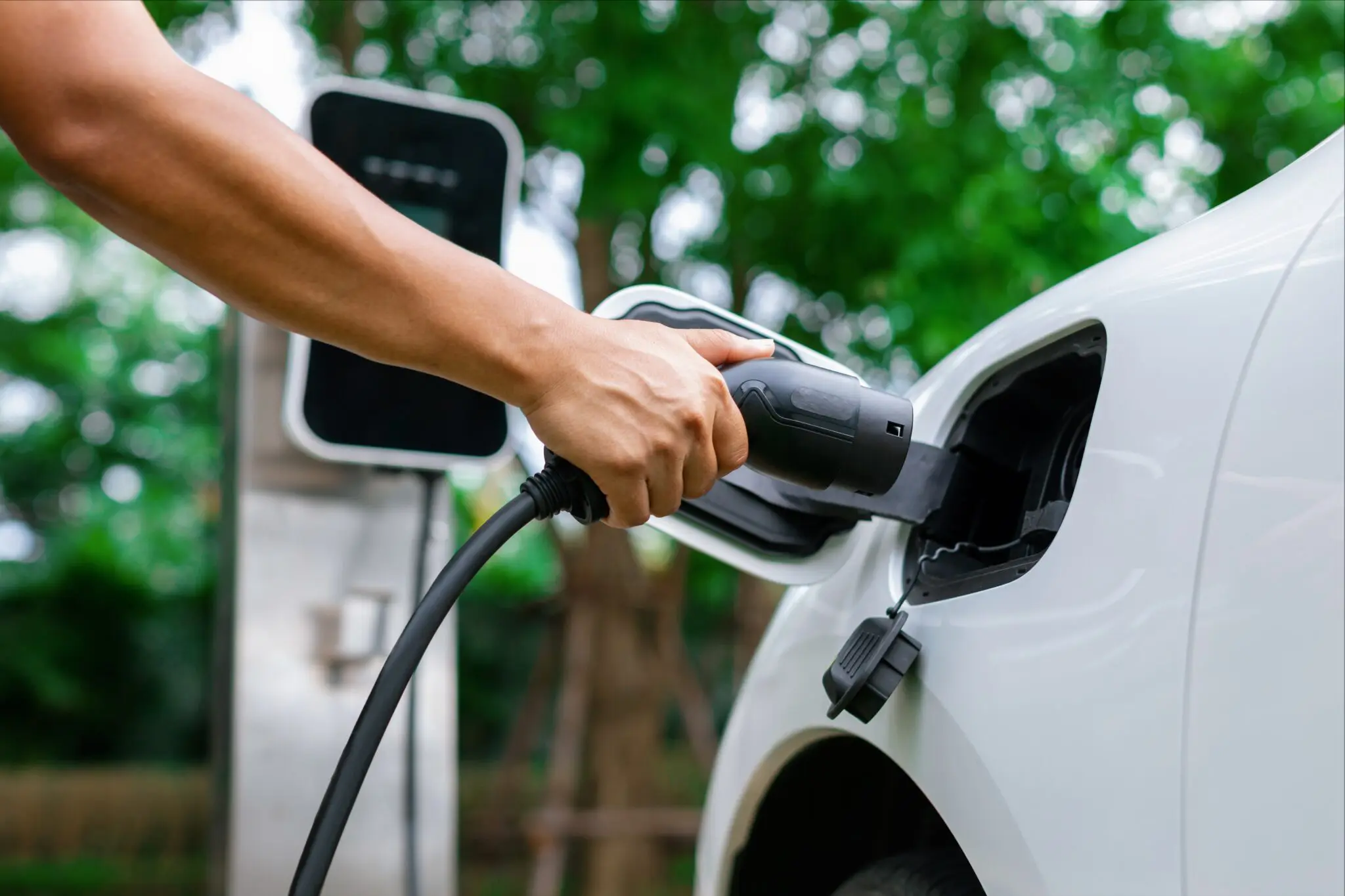 An electric vehicle being charged using an outdoor EV charger enclosure.